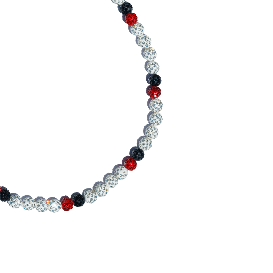 Necklace with alternating red, black, and white beads on a white background