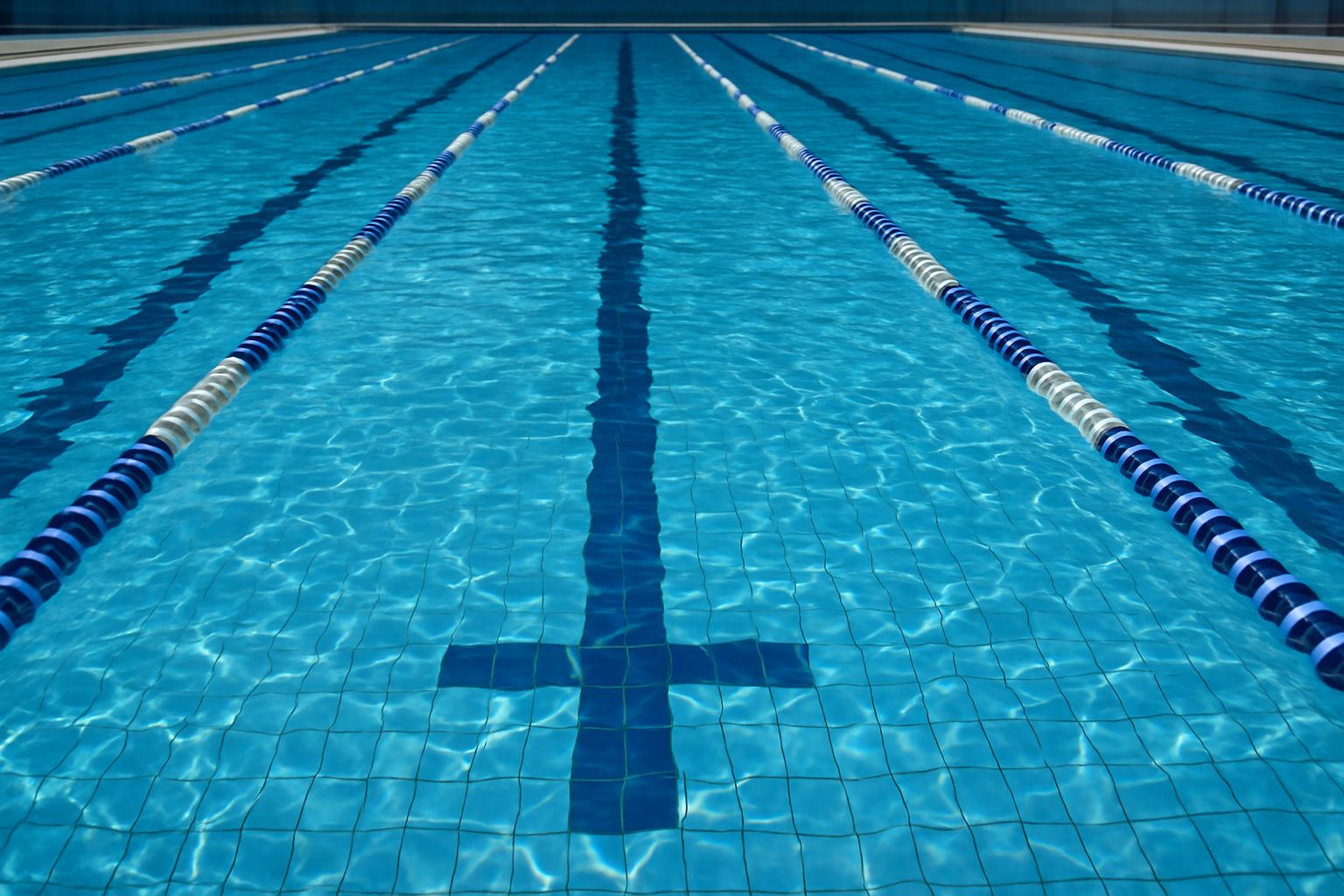 Olympic-style swimming pool with clear blue water and lane dividers, symbolizing the perfect backdrop for showcasing Christian swimming jewelry.