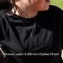 Person wearing a black shirt with a necklace featuring an all in faith softball script cross necklace