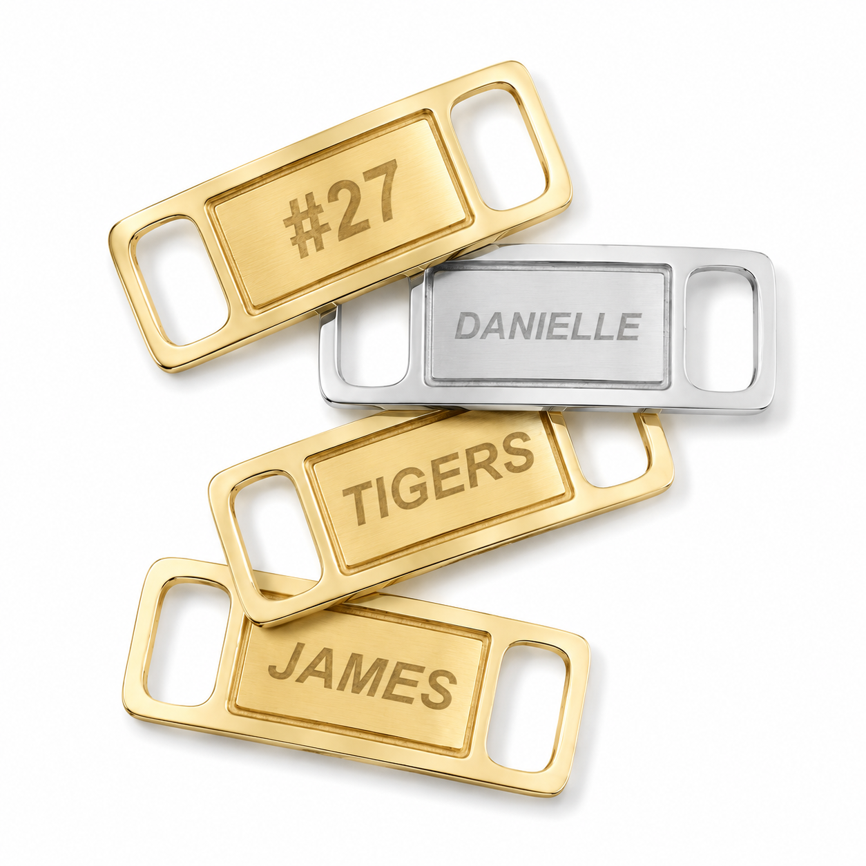 Four personalized belt buckle keychains arranged on a white background. Two are gold-toned with engraved names 'TIGERS' and 'JAMES', one is silver-toned with the name 'DANIELLE', and one is gold-toned with the number '#27'.