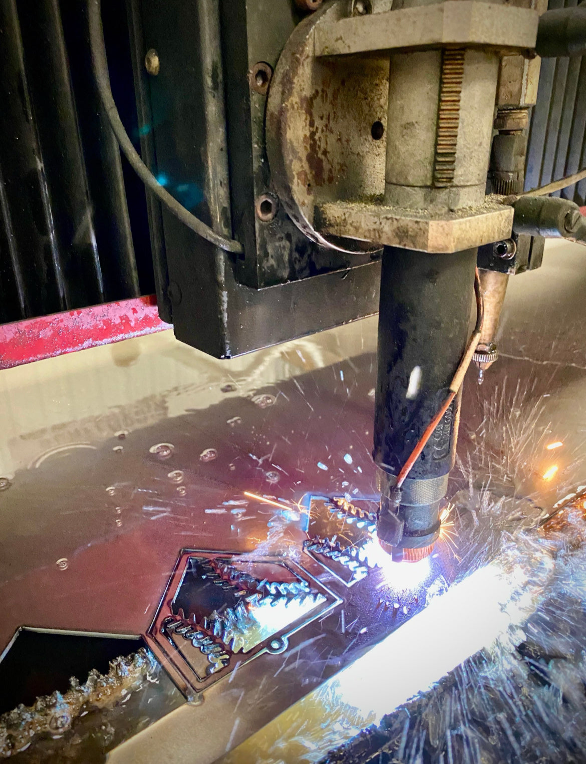 Plasma cutter creating the "STEEL HOME" Softball Christmas Ornament design from metal sheets.