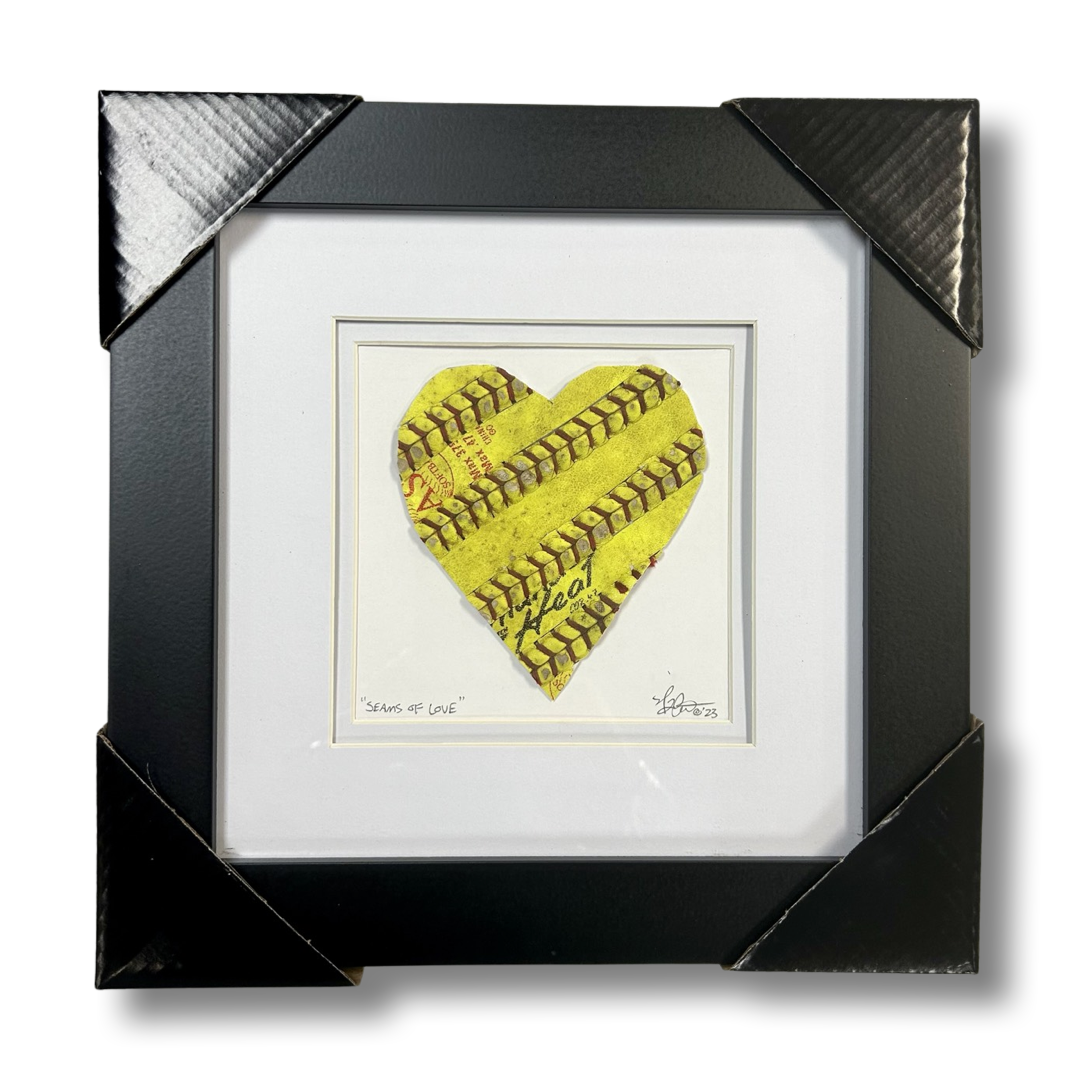 Softball Heart Artwork titled “Seams of Love” framed art piece featuring a heart design made from yellow softball leather.