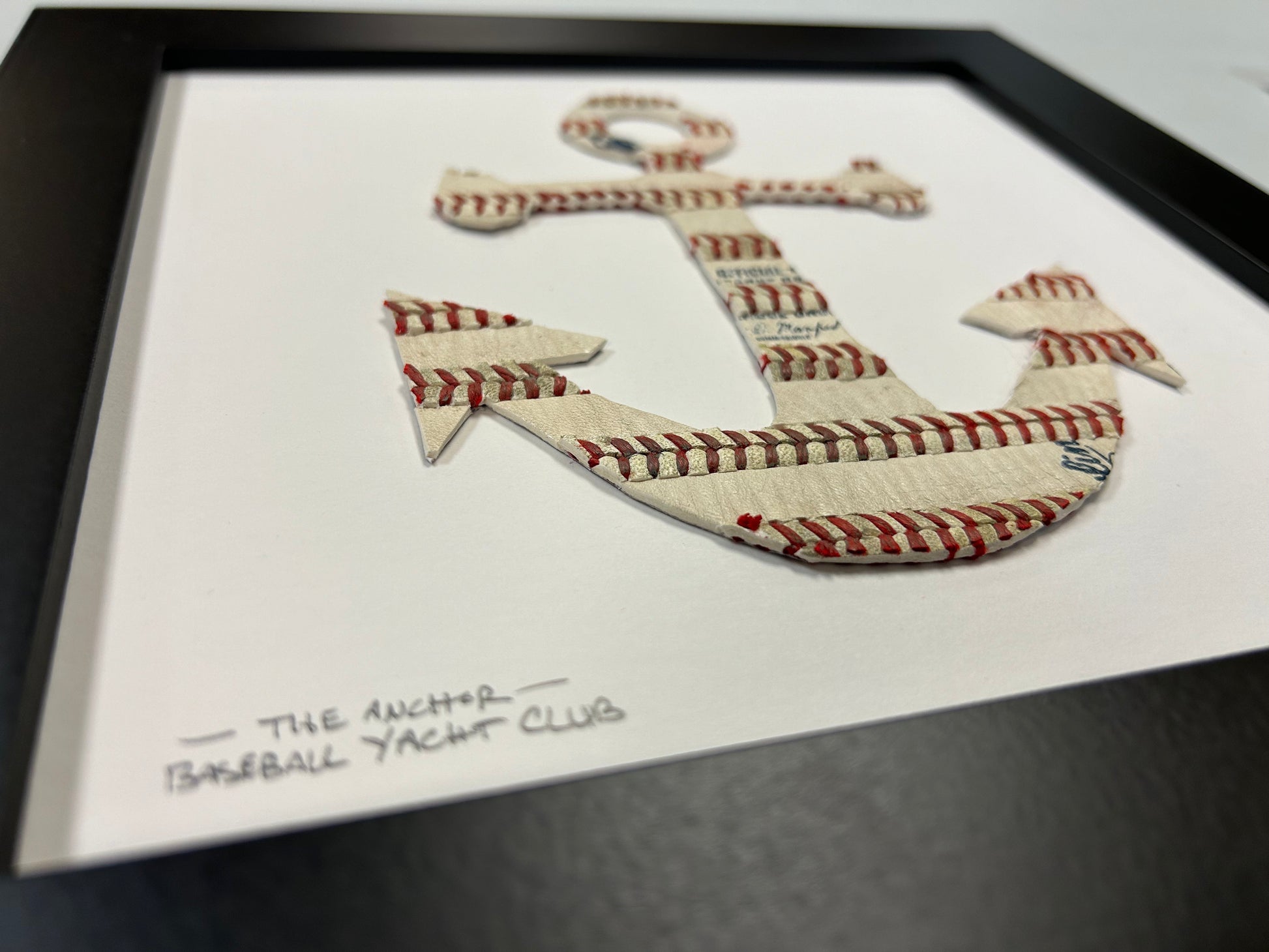 The Anchor Original Artwork - Made from Actual Used Baseballs framed in black, featuring a baseball stitch anchor design.