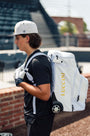 Luccini Baseball Wheeled Gear Bag – White | Baseball player wearing a white backpack with 'Lucchini' branding outdoors.