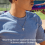 Person wearing a blue shirt with a necklace featuring a iced out Sterling Silver Catcher Mask pendant, holding a baseball bat.