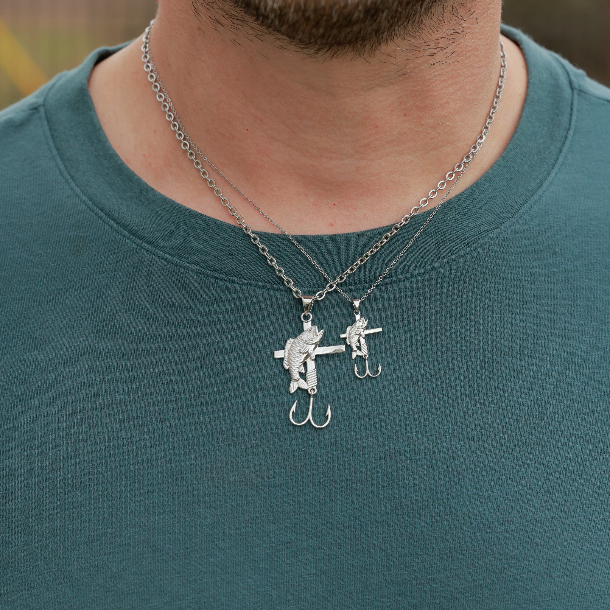 Person wearing a all in faith fisherman necklace with a unique pendant on a teal shirt