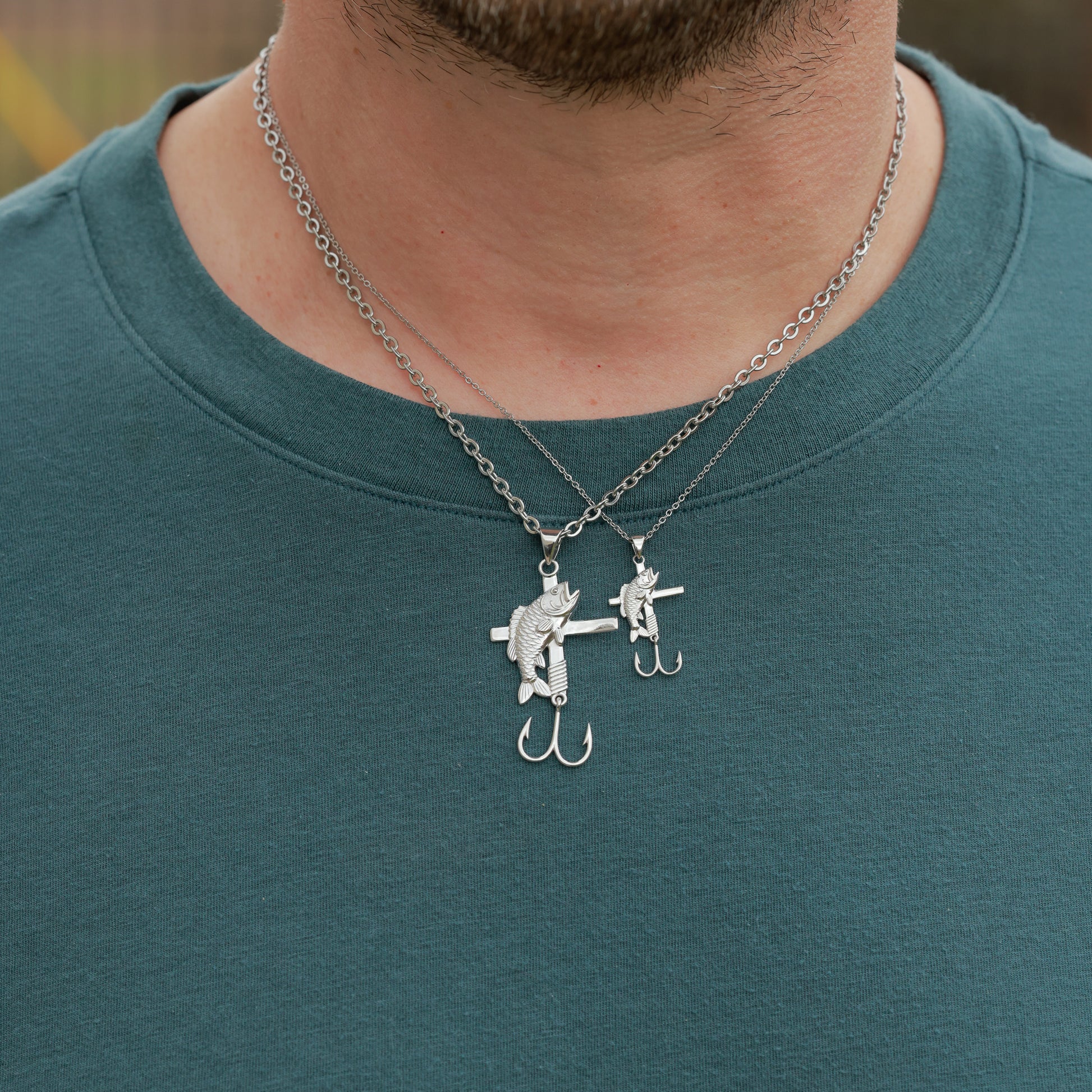 Person wearing a all in faith fisherman necklace with a unique pendant on a teal shirt