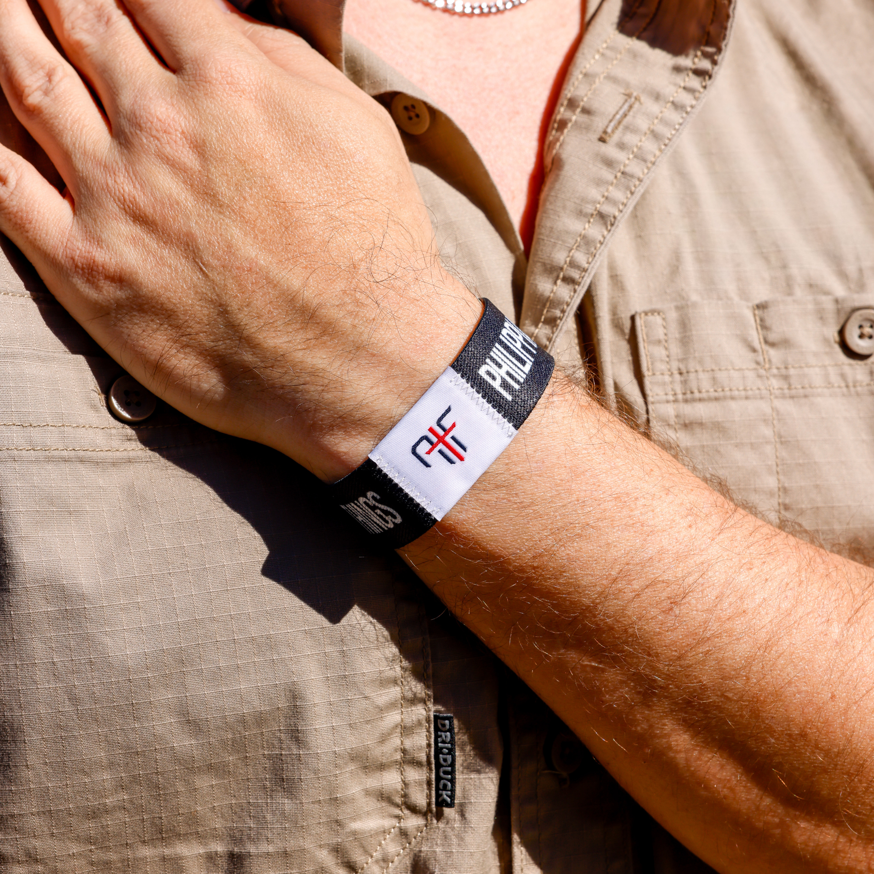 Person wearing a black wristband with AIF branding on a beige shirt background
