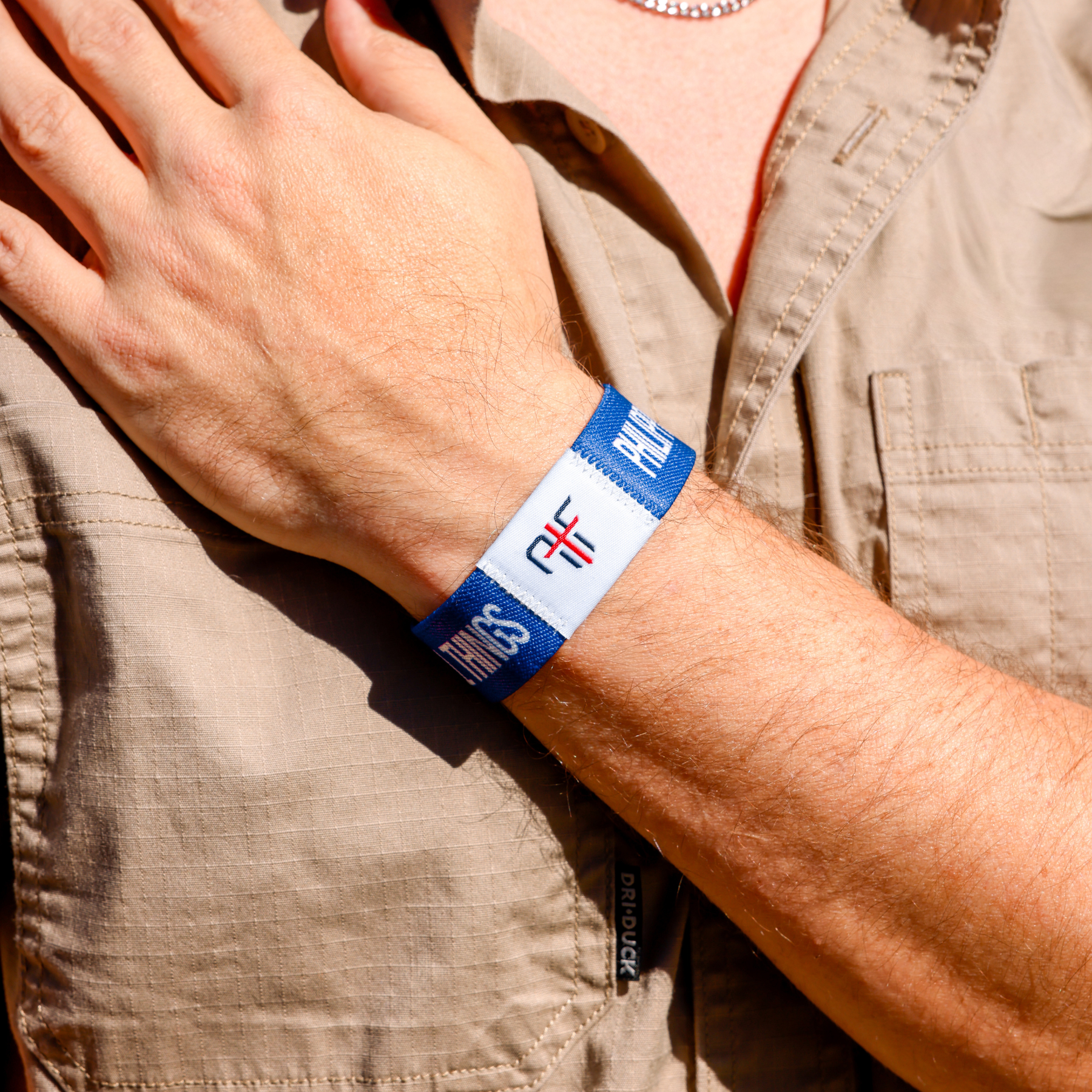 Person wearing a blue wristband with AIF branding on a beige shirt background