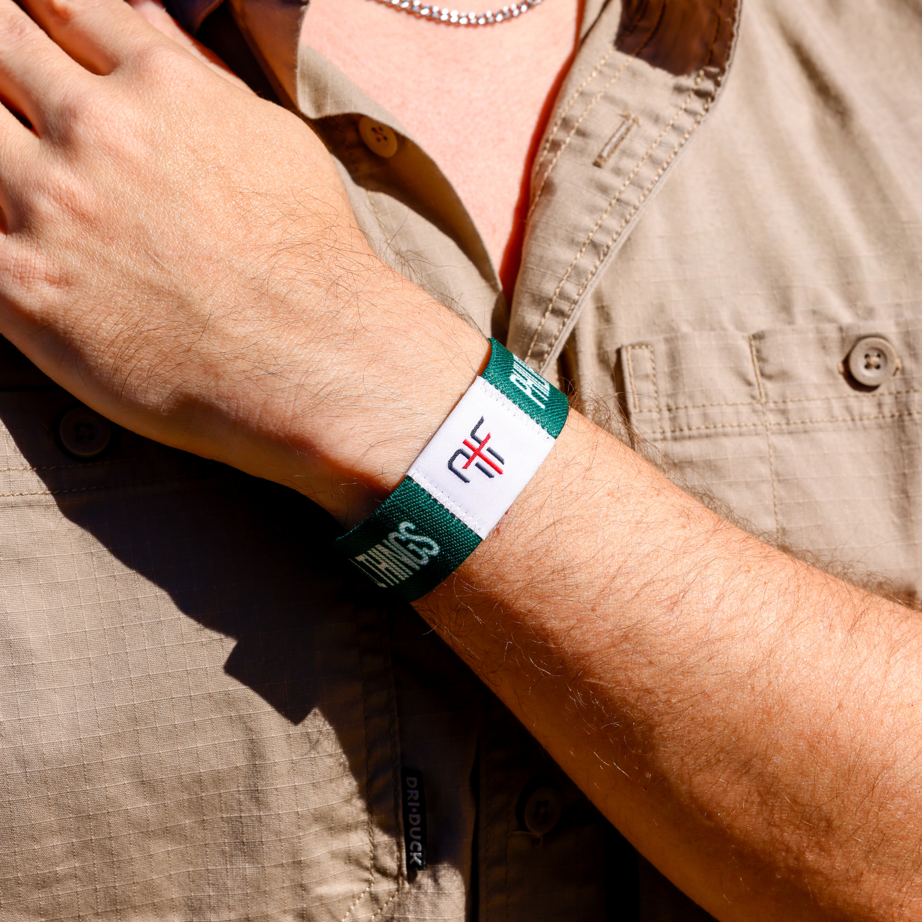 Person wearing a green wristband with AIF branding on a beige shirt background