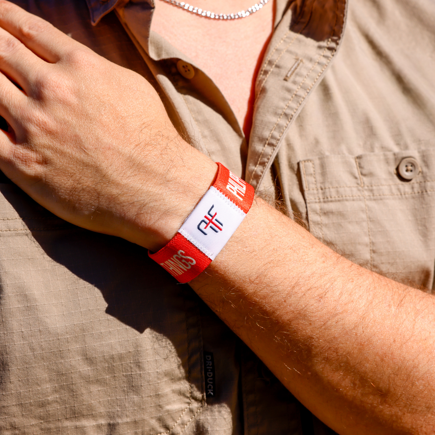 Person wearing a orange wristband with AIF branding on a beige shirt background