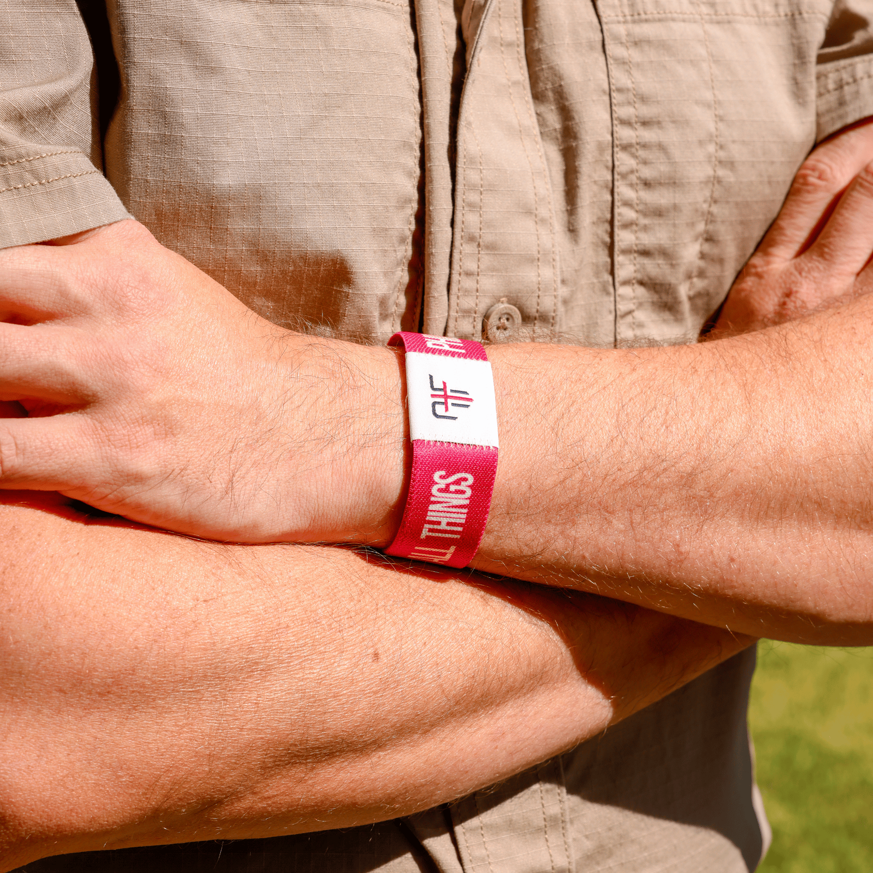 Person wearing a pink wristband with AIF branding on a beige shirt background