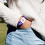 Woman wearing a purple wristband with AIF branding on a beige shirt background