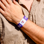 Person wearing a purple wristband with AIF branding on a beige shirt background