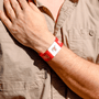 Person wearing a red wristband with AIF branding on a beige shirt background