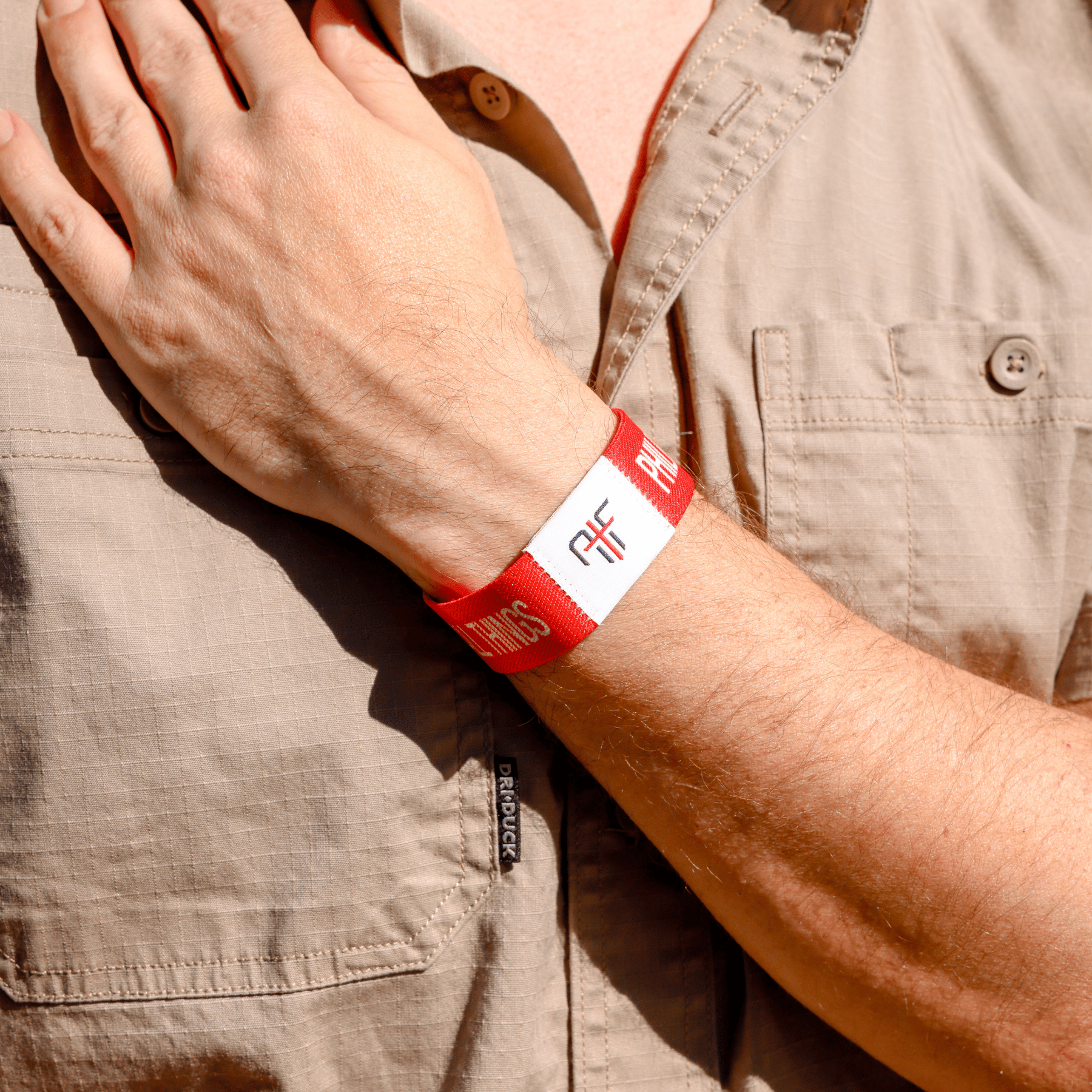 Person wearing a red wristband with AIF branding on a beige shirt background