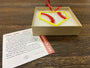 STEEL HOME" Softball Christmas Ornament in a gift box with a red ribbon and informational card.