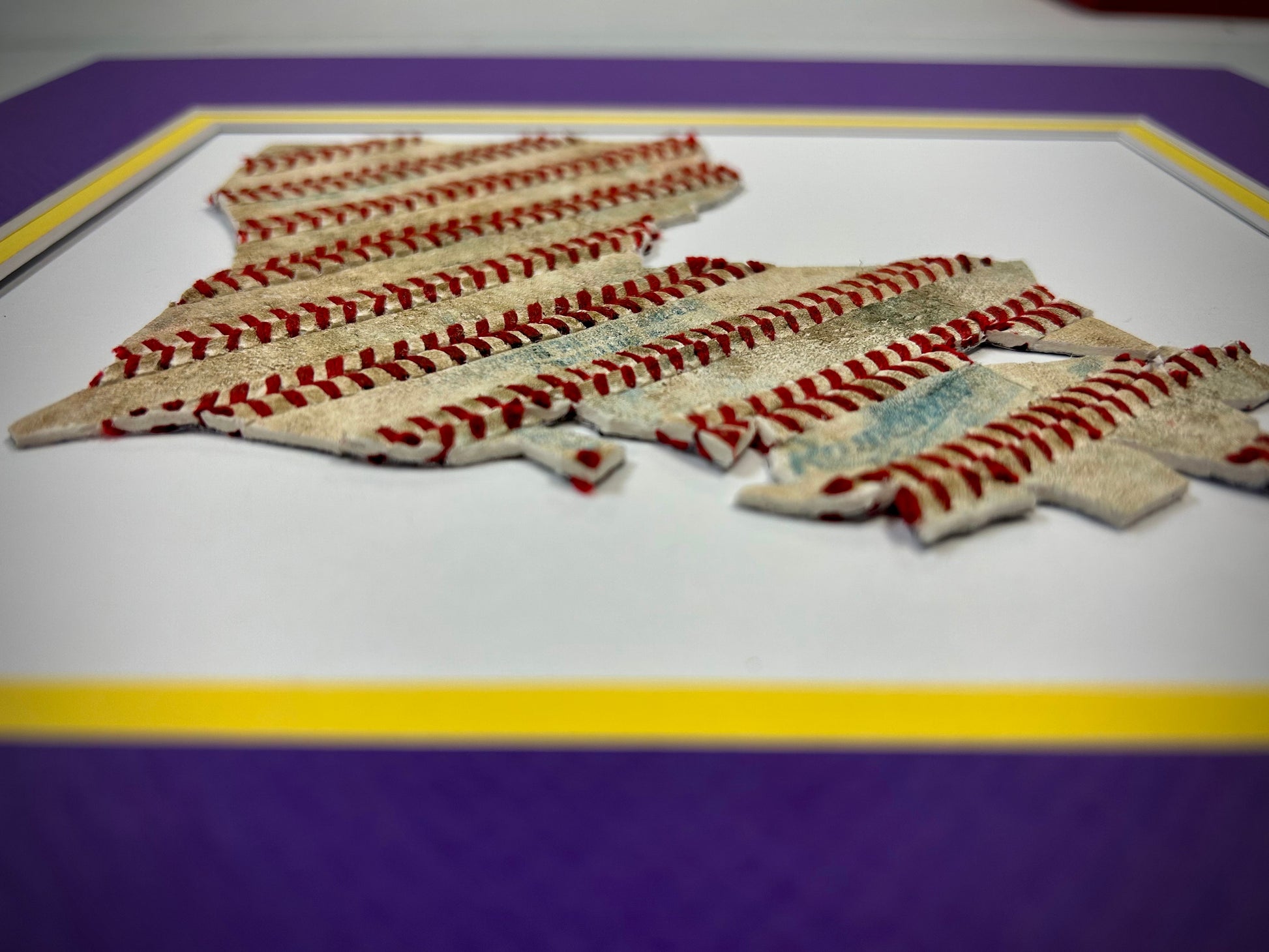 Custom State Artwork - Louisiana made from used baseballs, showcasing intricate design with baseball stitches in purple/gold matting.