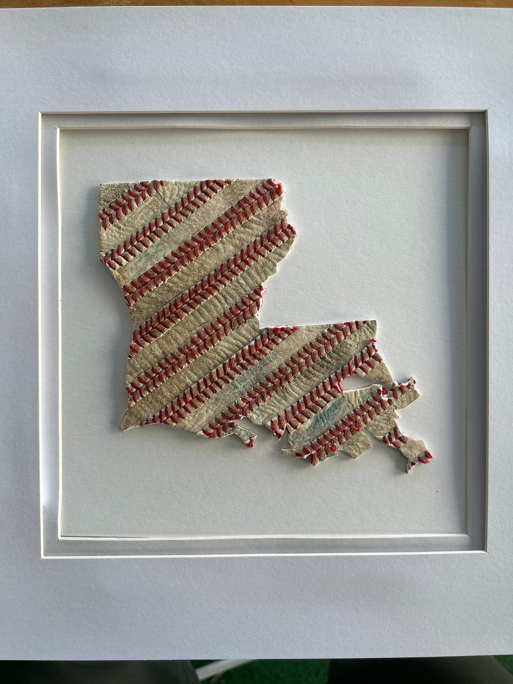 Custom State Artwork - Louisiana made from used baseballs, handcrafted art featuring baseball stitches, framed in white.