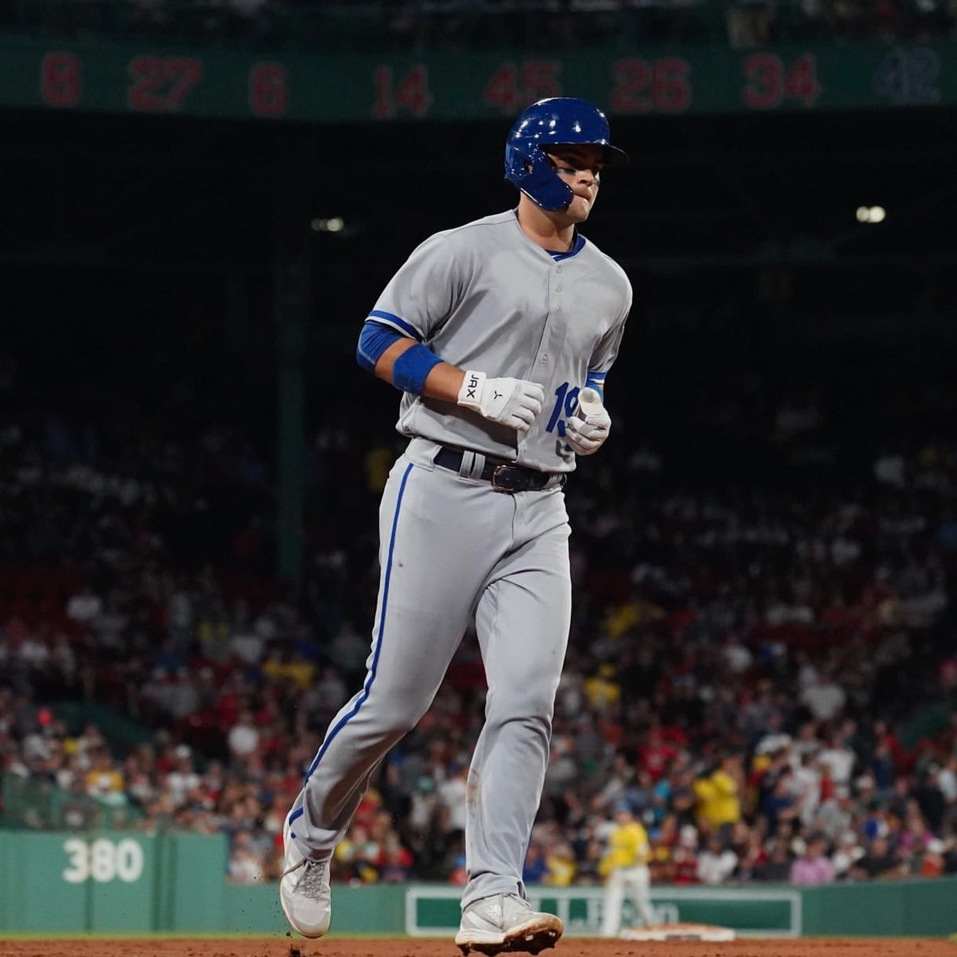 Jax Athletics Platinum White Baseball Gloves | Pro Cuff | Baseball player in gray uniform with blue helmet running on a field with spectators in the background